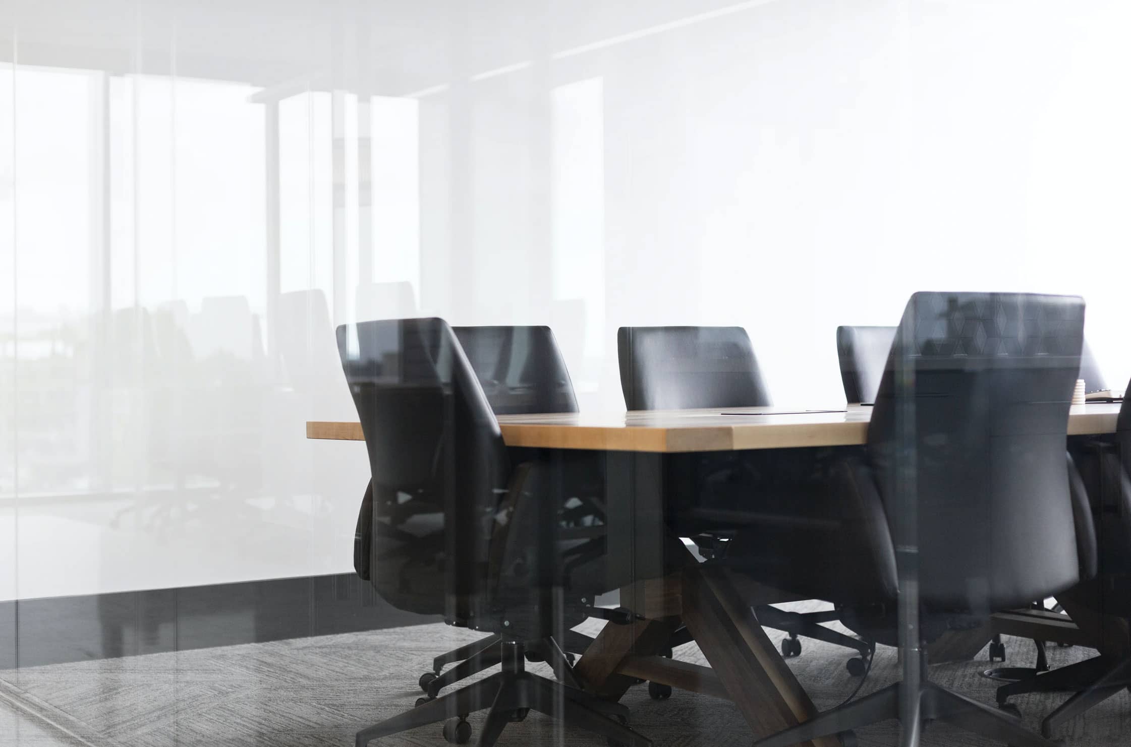 Conference Room Conference Room, Bilck durch eine Glasscheibe auf einen KOnferenztisch mit mehreren Leder-Bürostühlen darum